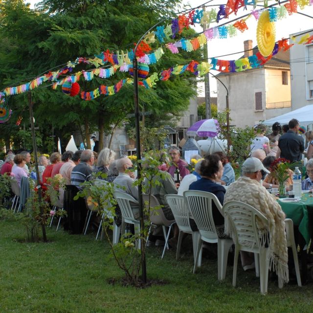 Repas festif des personnes de l'Ehpad dans le jardin avec des guirlandes