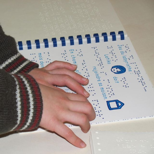 Main d'enfant lisant un livre en braille